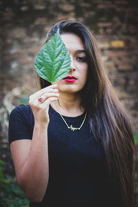 Portrait of beautiful woman holding leaves outdoors