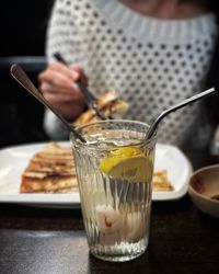 Midsection of person holding drink in glass on table