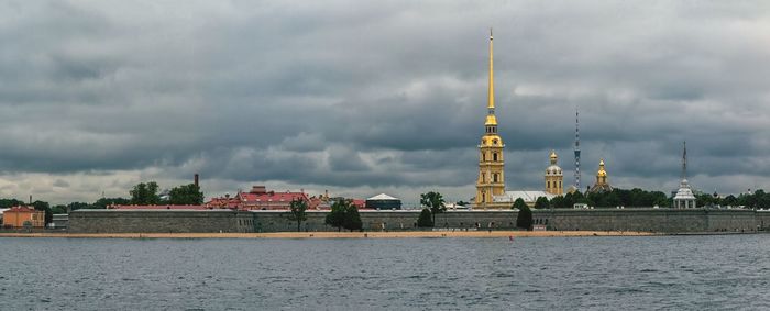 Low angle view of buildings in sea against cloudy sky