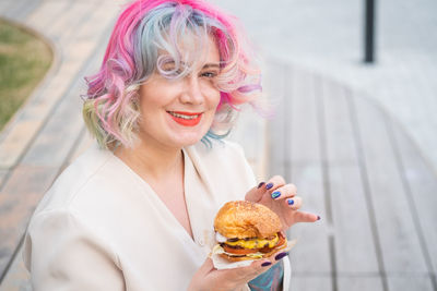 Woman holding burger outdoors