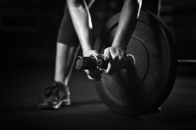 Low section of woman holding exercise equipment at gym