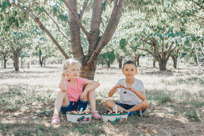 Boy and girl sitting by tree