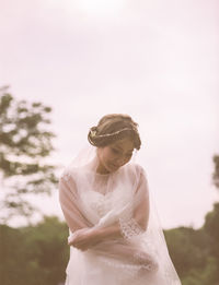 Smiling bride standing against clear sky