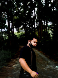 Side view of young man looking away in forest