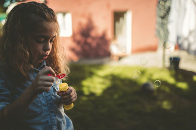 Close-up of girl blowing bubble in yard