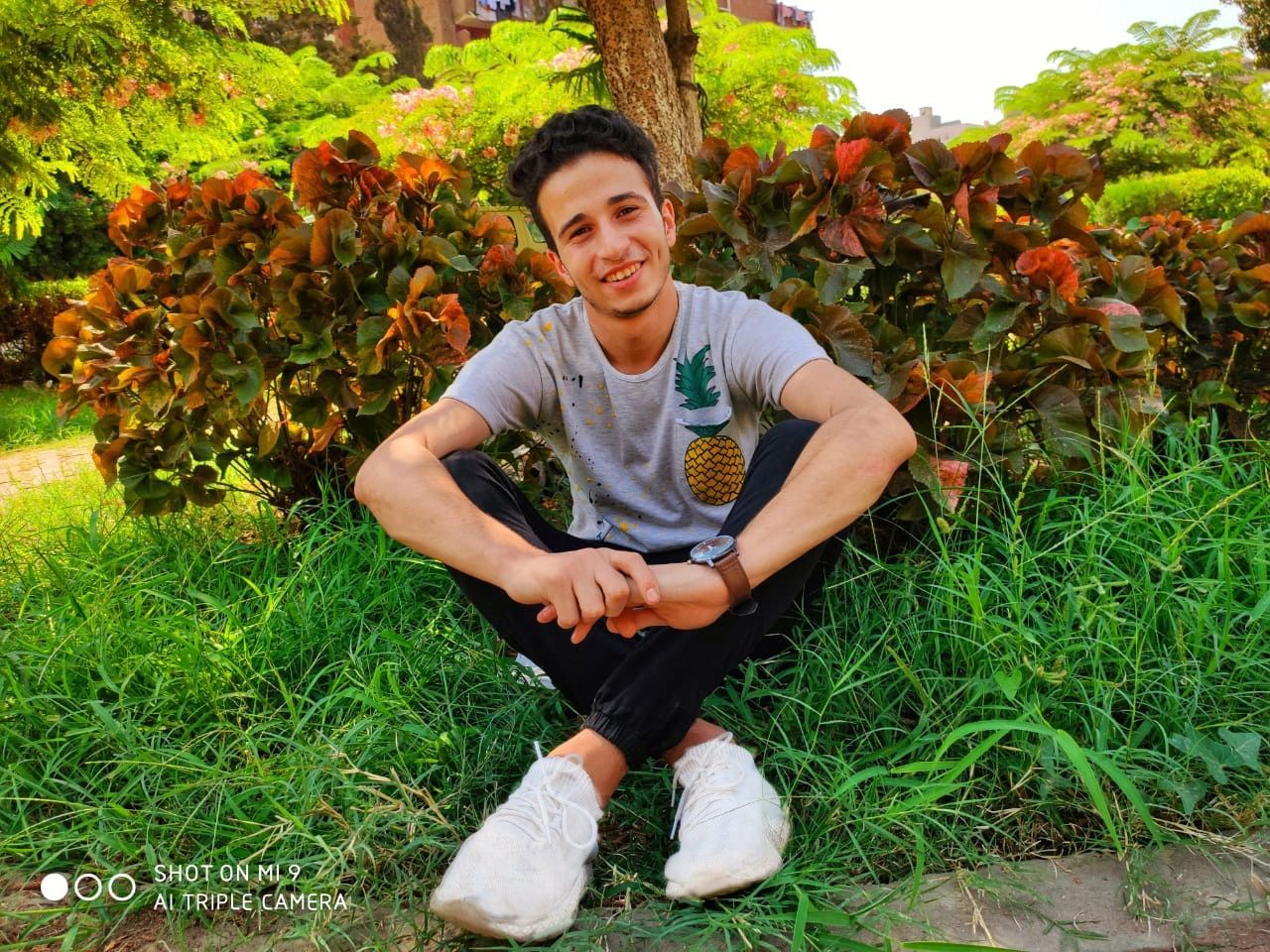 one person, plant, looking at camera, young men, young adult, smiling, portrait, leisure activity, front view, real people, full length, casual clothing, sitting, lifestyles, day, happiness, nature, grass, green color, outdoors