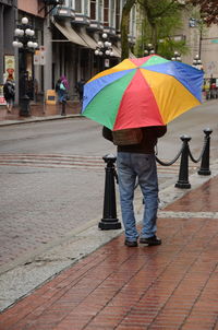 Rear view of woman walking on umbrella in city