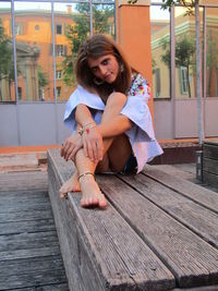 Full length of woman sitting on wood