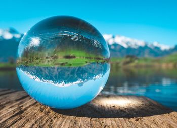 Close-up of blue ball on lake against sky