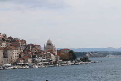 Buildings by sea against sky in city