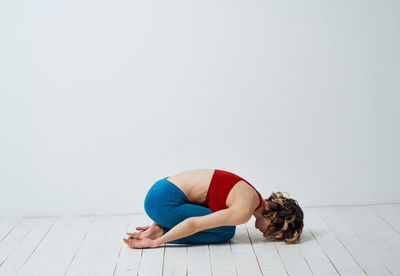 Rear view of woman exercising against white background