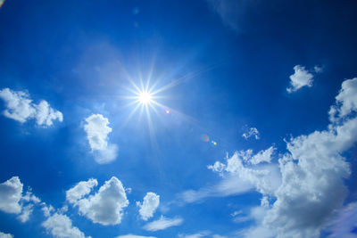 Low angle view of sunlight streaming through clouds