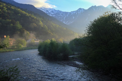 Scenic view of river amidst mountains against sky