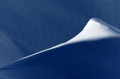 Close-up of snowcapped mountain against blue sky