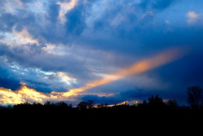 Silhouette trees against dramatic sky during sunset