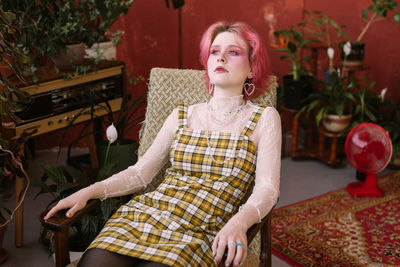 Young fashion stylish woman sitting on chair vintage studio, bright make up and colored hair