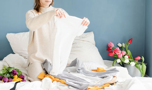 Low section of woman with white flowers on bed