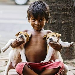 Portrait of cute boy with dogs sitting outdoors