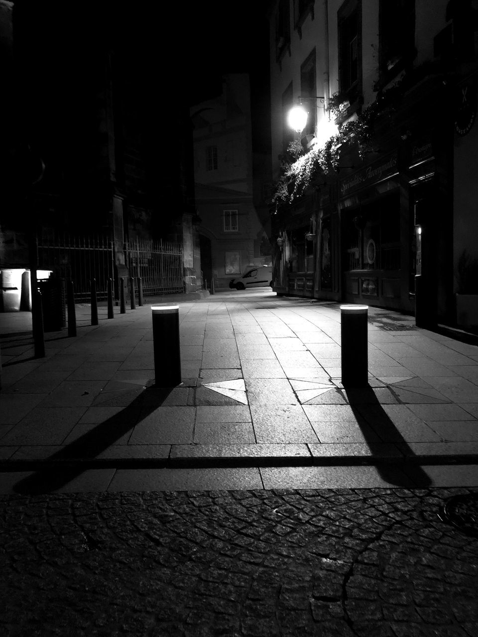 darkness, black, night, architecture, light, building exterior, street, built structure, white, city, illuminated, lighting, road, black and white, monochrome, footpath, street light, no people, monochrome photography, building, sidewalk, nature, transportation, outdoors, shadow, the way forward, city street, lighting equipment, city life, cobblestone