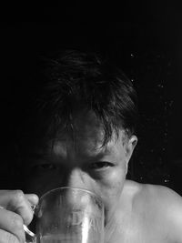 Close-up portrait of man drinking against black background