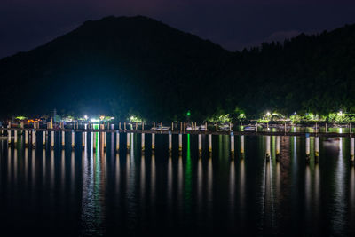 Reflection of illuminated trees in lake against sky at night