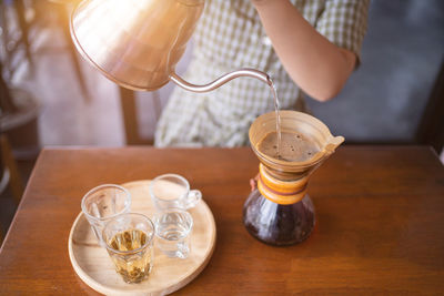 Midsection of woman having drink on table