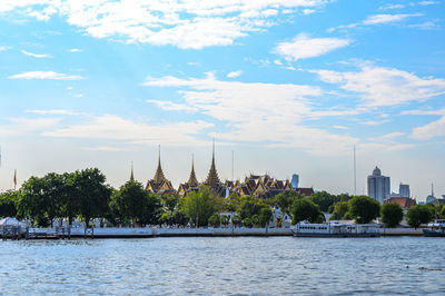 Scenic view of river by buildings against sky