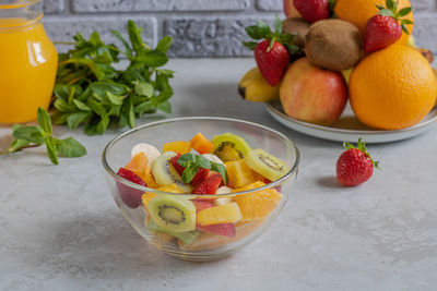  bowl with fruit salad. in the background is a fruit platter, natural juice and mint.