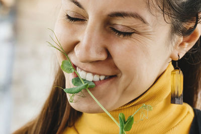 Happy woman eating freshly cut sprout of microgreen healthy eating superfood for vegan. diet concept