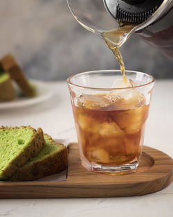 Close-up of iced tea in glass by breads on table