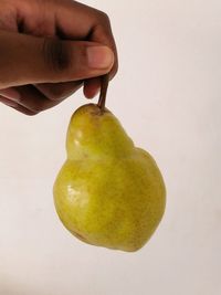 Close-up of hand holding apple against white background