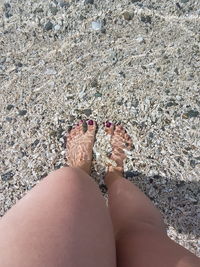 Low section of woman standing on sand