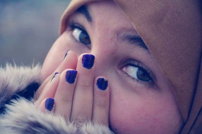 Close-up portrait of young woman covering nose