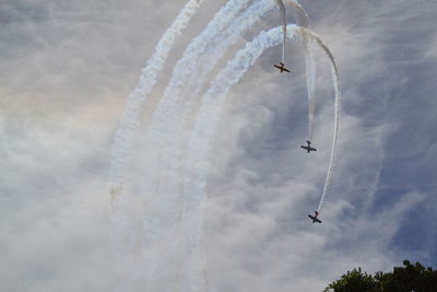 Low angle view of airshow against cloudy sky