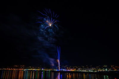 Firework display over river against sky at night