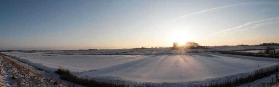 Panoramic view of snow field against sky during sunset