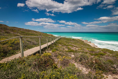 Scenic view of wooden footpath leading to sea at de hoop nature reserve south africa against sky