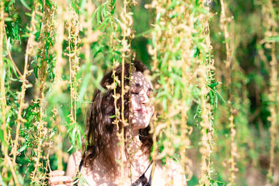 Woman with eyes closed standing by plants in park