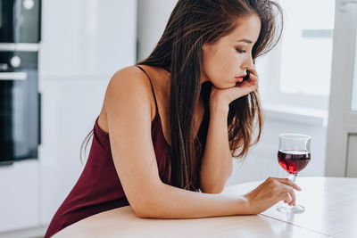 Young woman drinking glass on table