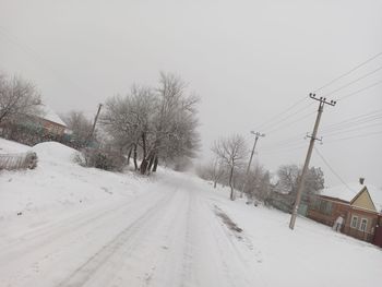 Road amidst snow covered trees against sky