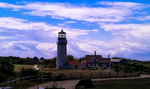 Lighthouse by building against sky