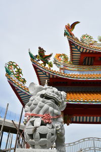 Low angle view of sculptures and roof of bang pa-in royal palace against clear sky