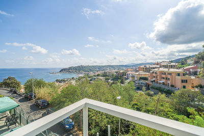 High angle view of townscape by sea against sky with green trees