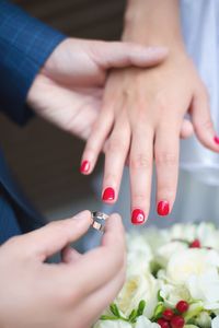 Cropped image of bridegroom putting ring in hand of bride