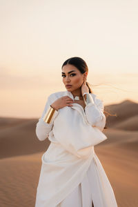 Portrait of young woman standing against orange sky