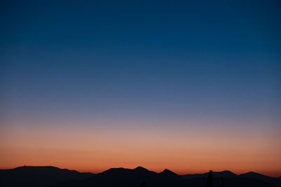 Scenic view of silhouette mountains against clear sky at sunset