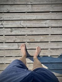 Low section of man relaxing on wooden pier