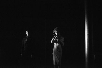 Woman standing against black background