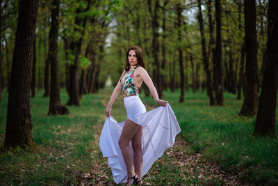 Full length of woman on field by trees in forest