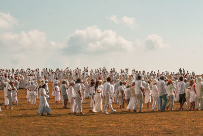 Group of people on field against sky